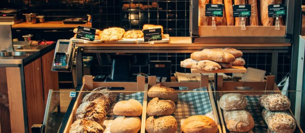 Des pains et des viennoiseries dans des paniers en bois le long d'un comptoir de boulangerie.