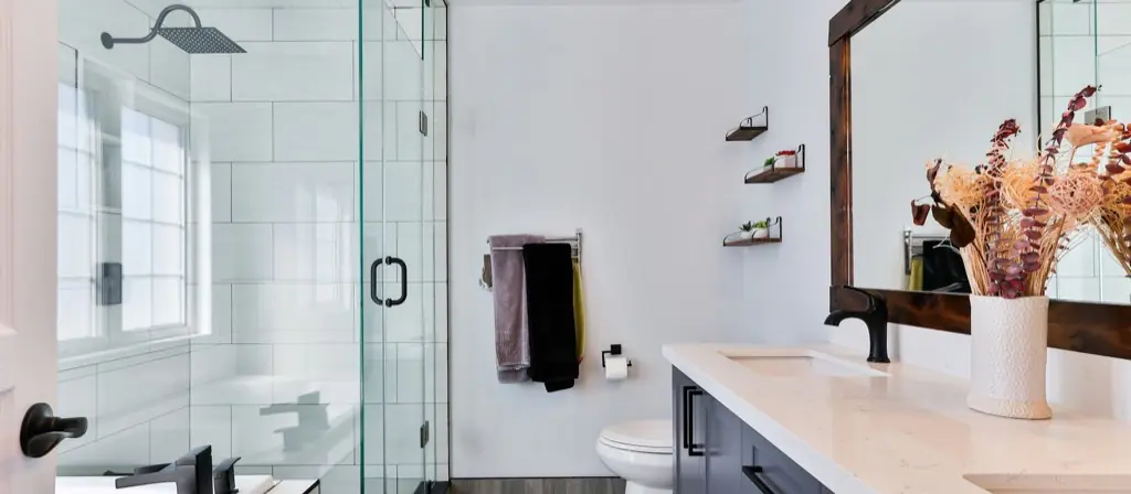 Une salle de bain moderne et propre avec une douche vitrée et un long meuble-lavabo.