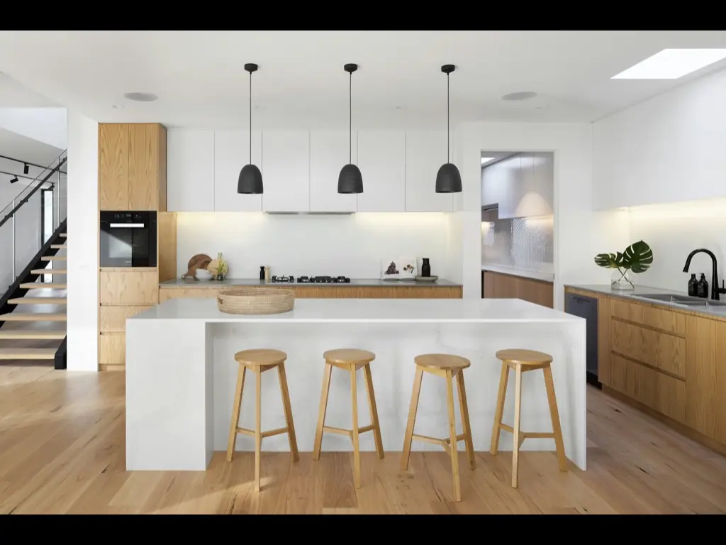 Une cuisine moderne avec un grand îlot et des tabourets sous des luminaires suspendus.